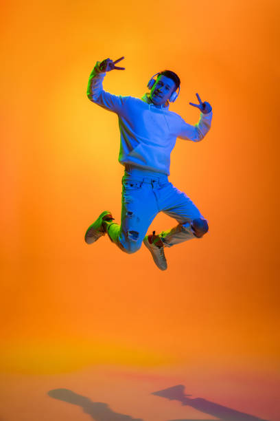 Caucasian beautiful man's portrait isolated on yellow studio background in multicolored neon light