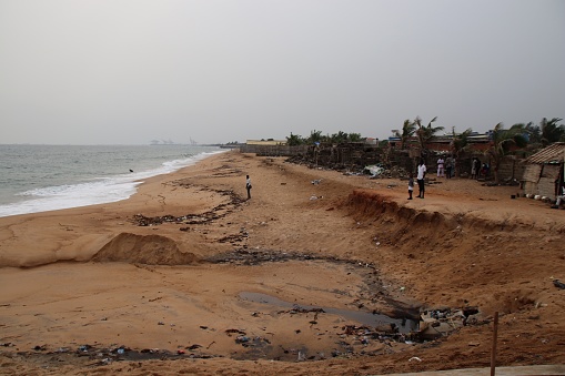 Avepozo, Togo - Februrary 19, 2019: Eroded beach of Avepozo, Togo, West Africa. People walk at the beach.
