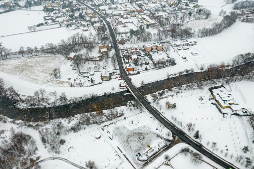 Aerial view of the snowy landscape with a road bridge over the Mała Panew river in Opole - Czarnowasy in winter.