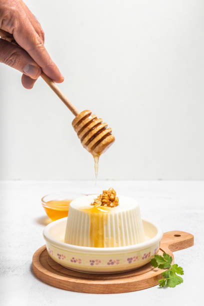 Man's hand pouring honey into a fresh cheese on a white background Man's hand pouring honey into a fresh cheese on a white background cottage cheese photos stock pictures, royalty-free photos & images