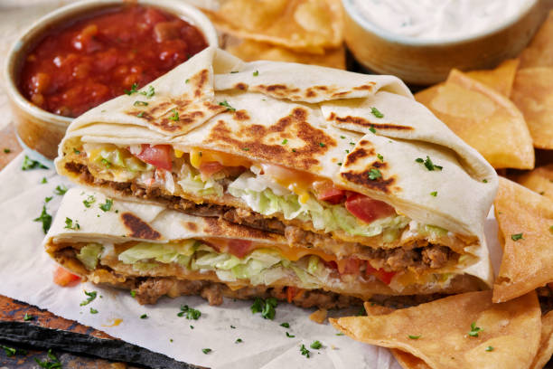 The Cheesy Beef Crunch Wrap Supreme The Copycat Crunch Wrap Supreme with Spicy Ground Beef, Cheese, Lettuce, Tomato, Sour Cream, Salsa Con Queso with a Crispy Corn Tortilla in the Middle fajita photos stock pictures, royalty-free photos & images