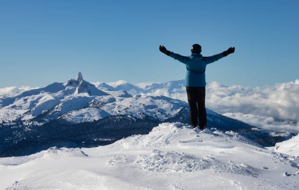 Adventurous Girl on top of a beautiful snowy mountain Adventurous Girl on top of a beautiful snowy mountain during a vibrant and sunny winter day. Hands Up. Taken in Whistler, British Columbia, Canada. whistler mountain stock pictures, royalty-free photos & images