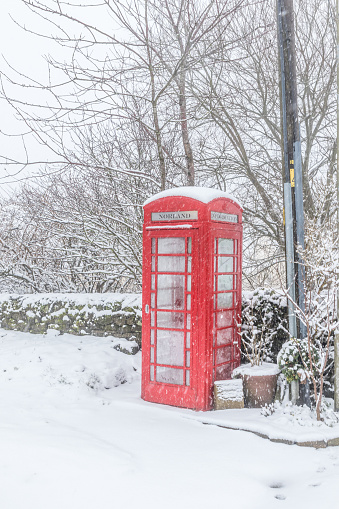 A traditional red British telephone box in the snow in winter