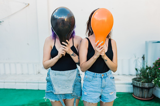Two girlfriends have fun with colored balloons. White background not isolated