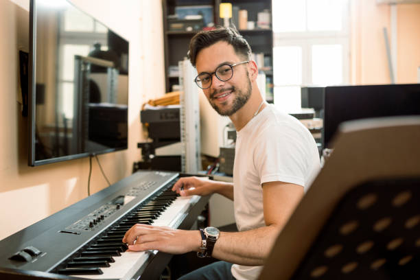 istock Young passionate man playing electric piano ,looking at notes 1301436219