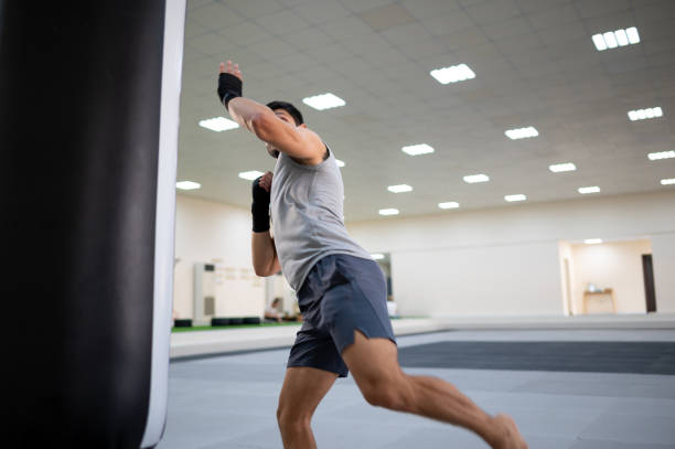 istock Male boxer kicking a boxing bag during a kick box or boxing training 1301436547