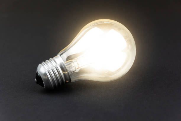 istock a lighted light bulb lies on a black cardboard 1301439022