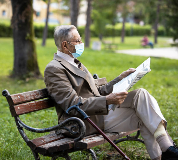 istock An old man is sitting on a bench resting reading a newspaper 1301439272