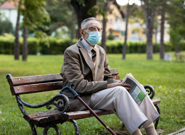 istock An old man is sitting on a bench resting reading a newspaper 1301439277