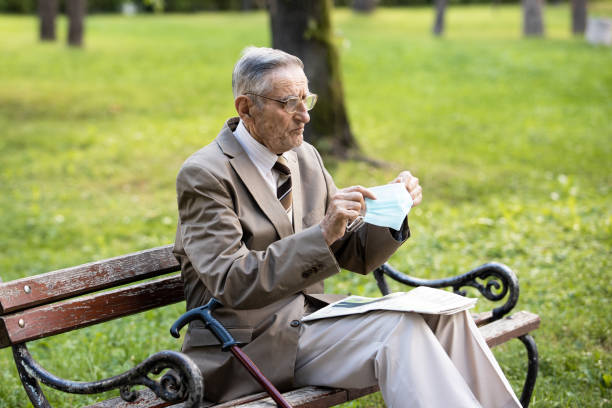 istock An old man is sitting on a bench resting reading a newspaper 1301439331