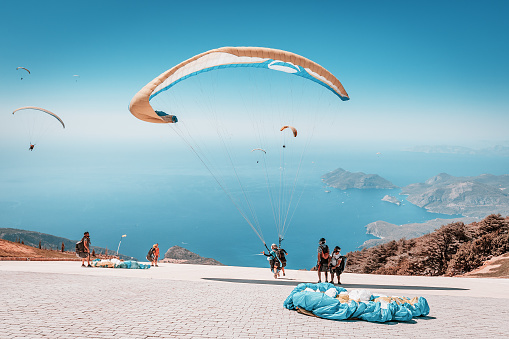 09 September 2020, Babadag, Oludeniz, Turkey: Many paragliding adventurers takeoff in tandem with instructor after a short training session for recreational flight and descent to the sea