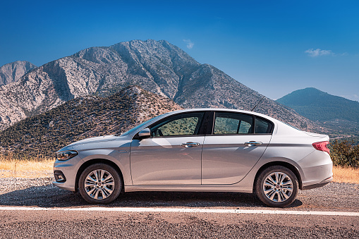 12 September 2020, Termessos, Turkey: Fiat Egea passenger car parked on the background of the Taurus Mountains. Car rental and travel concept