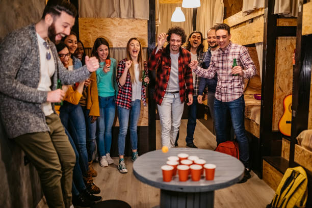 istock Young people playing beer pong in hostel 1301443910