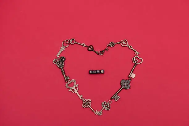 Photo of The heart is laid out of the keys to the locks on a red background. Valentine's Day greeting card. Top view