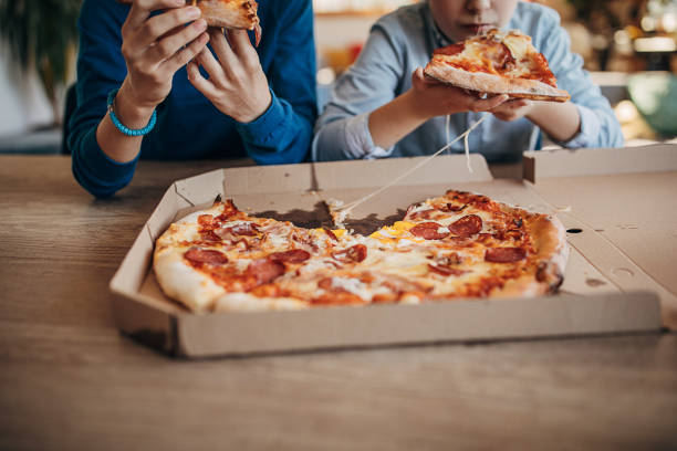 istock Two brothers eating pizza together 1301444678