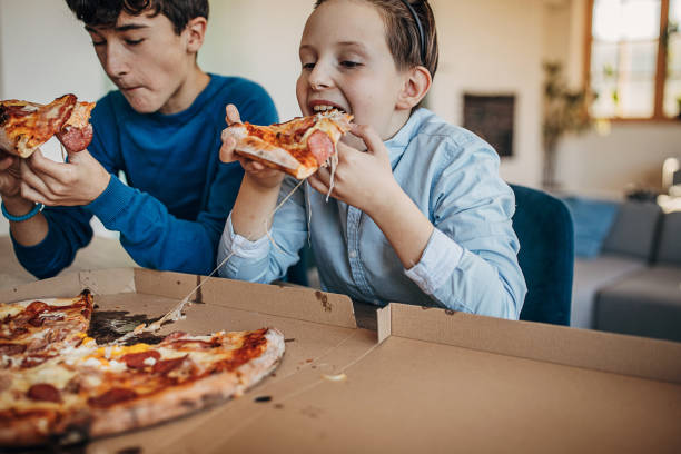 istock Two boys eating pizza together 1301444733