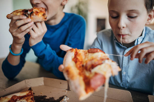 istock Two boys eating pizza together 1301444750