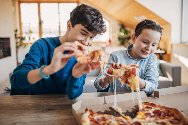 istock Two boys eating pizza together 1301444765