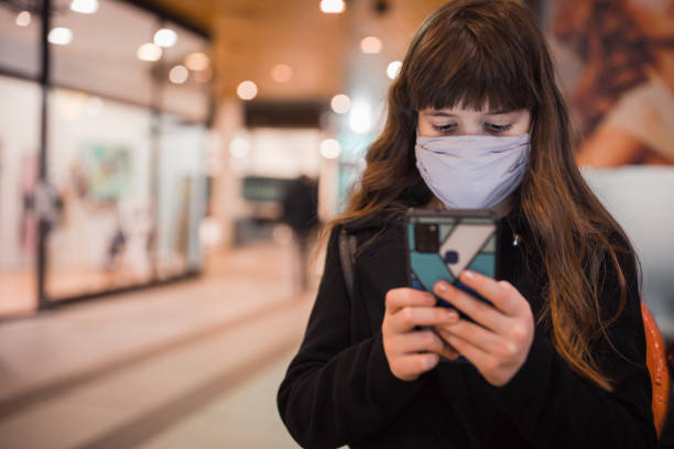 istock Girl wearing protective mask and text messaging 1301455770