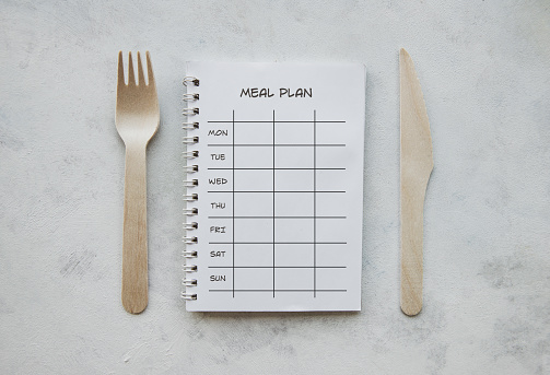 Ring binder, fork and knife on the white background.