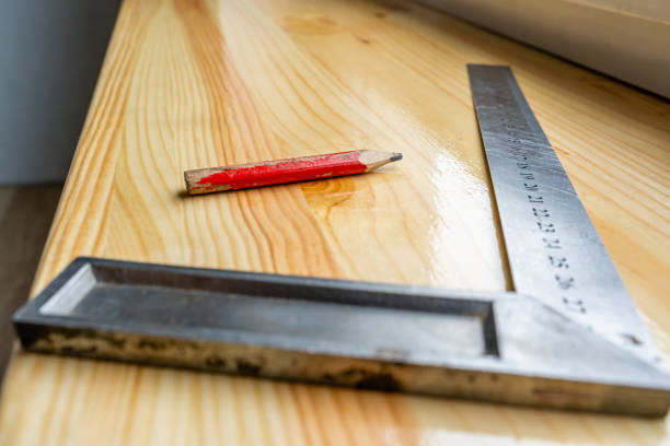 Red Carpenter's Pencil and Right Angle's Tool on Laminate Floor after Renovation or Reconstruction Work.- Selective Focus
