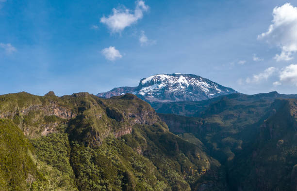 tiro aéreo de um cume mais alto do continente africano - vulcão kilimanjaro uhuru peak 5895m coberto de neve. ponto de vista do drone voando até 3600m. rota umbwe, parque nacional tanzaniano - 5895 - fotografias e filmes do acervo