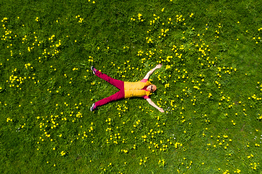 Woman lying in spring meadow, aerial top view.