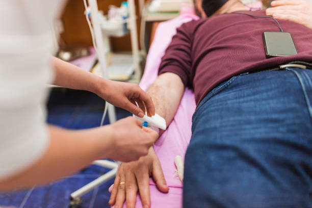 Patient getting help from a nurse sticking IV  drip into his arm