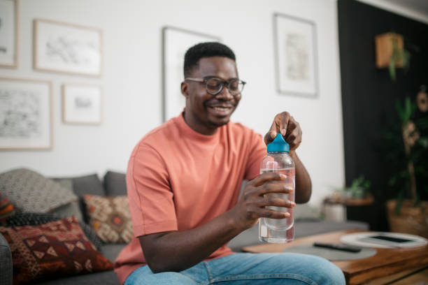 istock Happy young African American man drinking water at home 1301464148