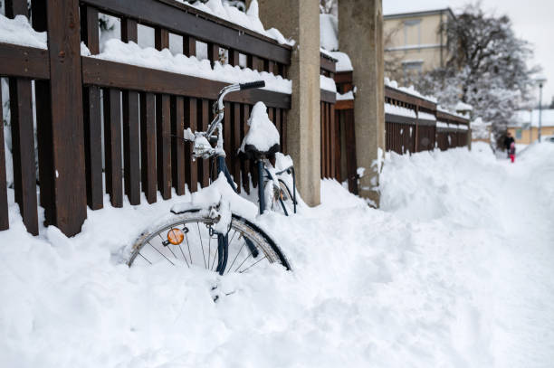 Thuringia, Germany: A bike is leaning against the fence in winter and is covered with snow.