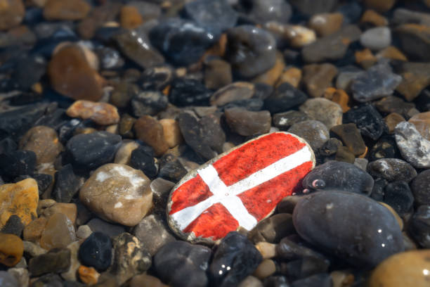 dänemark banner auf einem stein am strand im wasser - denmark house flag danish flag stock-fotos und bilder