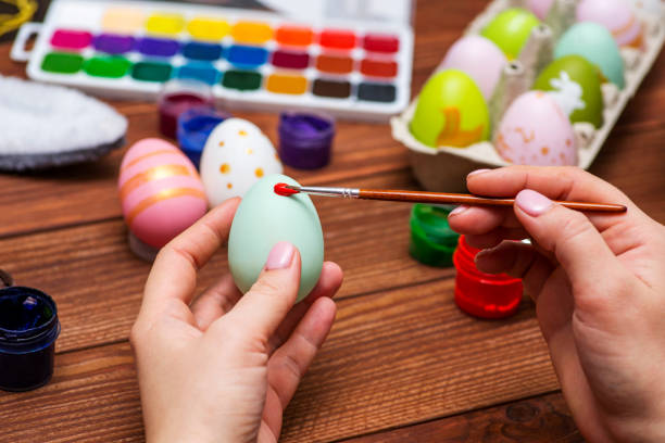 istock A woman with a tassel paints Easter eggs. Preparing decorations for Easter, creativity with children, traditional symbols. Preparing for Easter. 1301470477
