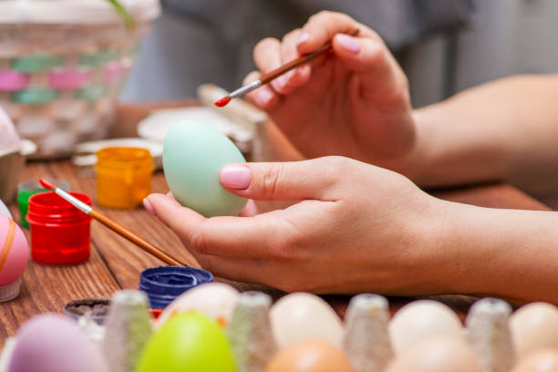 istock A woman with a tassel paints Easter eggs. Preparing decorations for Easter, creativity with children, traditional symbols. Preparing for Easter. 1301470513