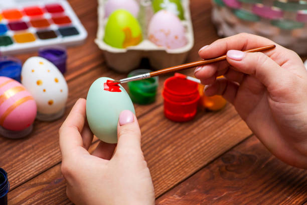 istock A woman with a tassel paints Easter eggs. Preparing decorations for Easter, creativity with children, traditional symbols. Preparing for Easter. 1301470530