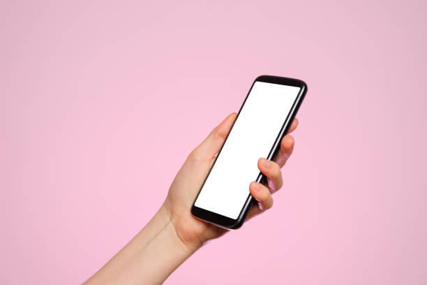 istock Smartphone with a blank screen in a woman's hand on a pink background. 1301471867