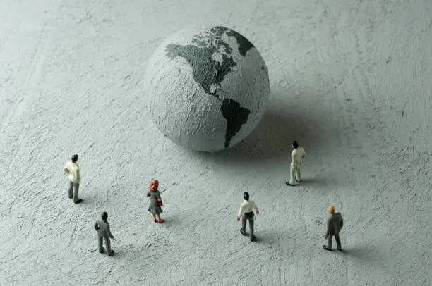 Businessman/Politician figurines examine a concrete globe (Americas)
