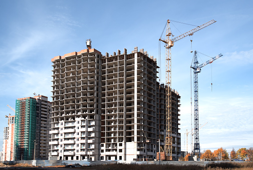 Construction site with buildings and cranes at blue sky background
