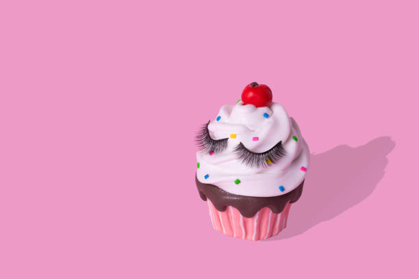istock Creative minimal artwork of colorful cupcake with eyelashes on pastel pink  background. 1301475310