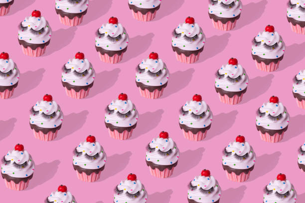 istock Trendy colorful cupcake with eyelashes pattern on pink background. 1301475328