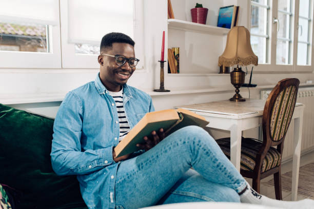 istock Happy man reading a book at his living room 1301479891