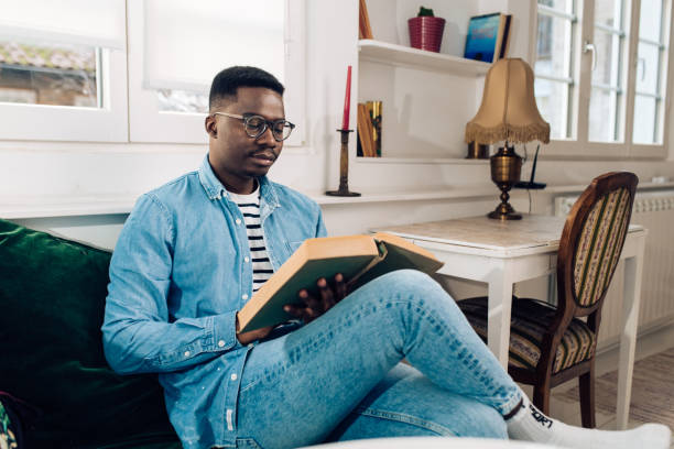 istock Young African American enjoying reading at home 1301479892