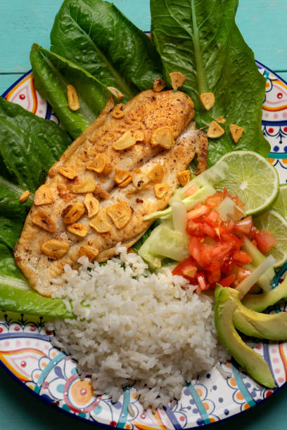istock Fish steak with garlic, salad and rice on turquoise background 1301482110