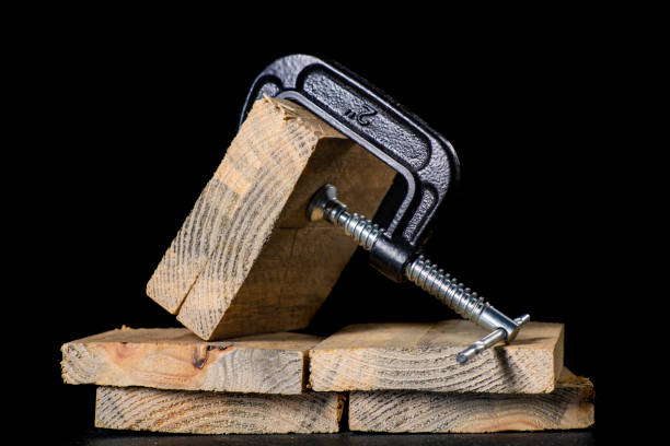 A metal clamp used to hold pieces of wood in place. Carpentry accessories in the workshop. Dark background. A metal clamp used to hold pieces of wood in place. Carpentry accessories in the workshop. Dark background. c clamp photos stock pictures, royalty-free photos & images