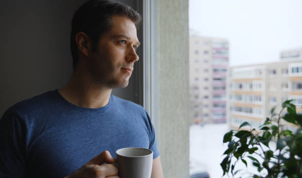 istock Man with cup of tea looks out the window. 1301489313