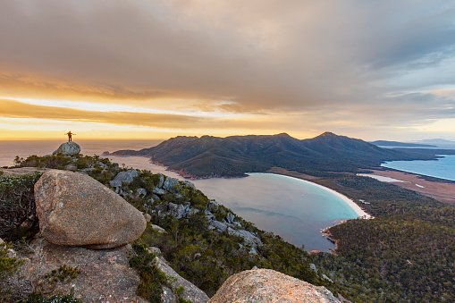 Hiker on top of mountain at sunrise, wineglass bay Tasmania, Australia