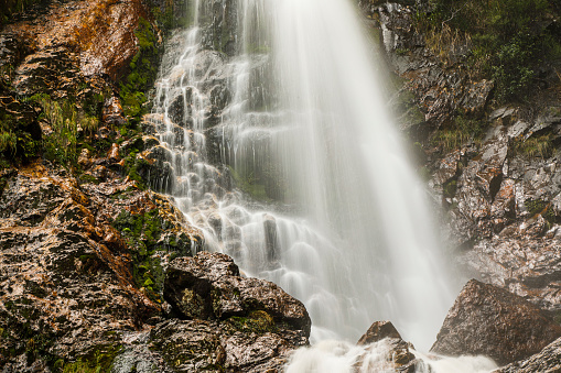Up close idyllic flowing waterfall with moss and dense green rainforest environment, Tasmania, Australia