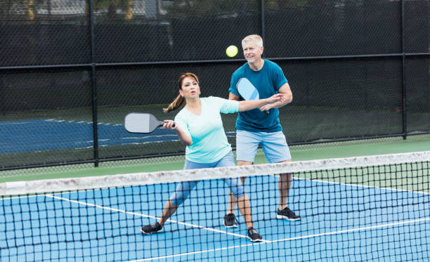 para gra pickleball, latynoska kobieta uderza piłkę - latin american and hispanic ethnicity senior adult mature adult couple zdjęcia i obrazy z banku zdjęć