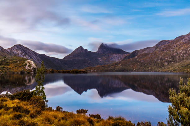 istock Colourful mountain range reflected in still lake with pink sky 1301501882