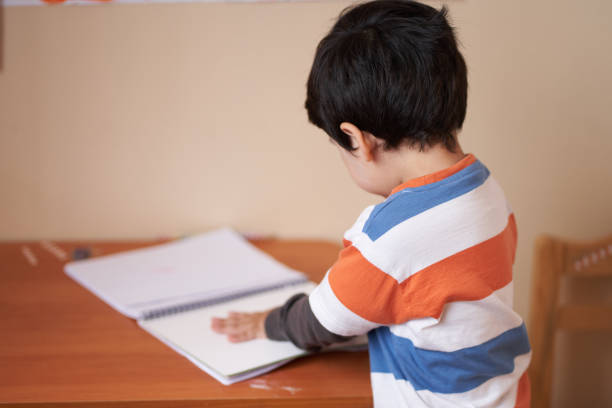 istock boy in striped T-shirt with his back to the camera doing activities in his study notebook 1301503213