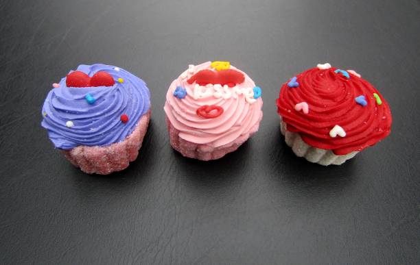 Purple, pink and cupcake shaped marshmallow candies on black background.